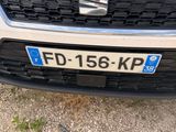 the front end of a white car with a number plate on it