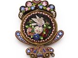 une photo d'une broche ornée d'un oiseau et de fleurs