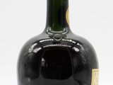 an old bottle of liquor sitting on top of a white surface