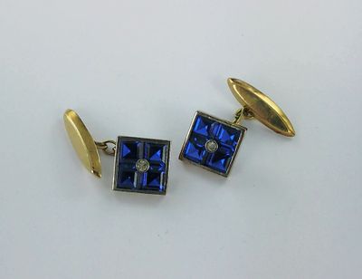 une paire de boutons de manchette bleus et dorés sur un fond blanc