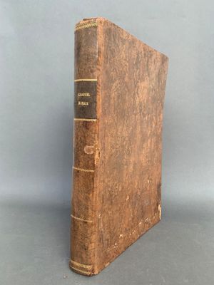 un vieux livre posé sur une table à côté d'un mur gris