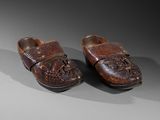pair of wooden clogs with carvings on them on a gray surface