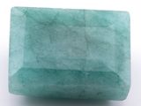 un gros plan d'une pierre verte sur une surface blanche