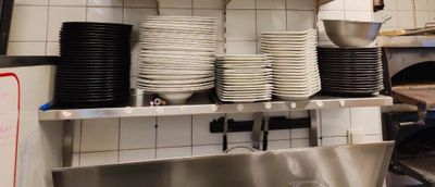 de nombreuses assiettes et casseroles empilées sur une étagère dans une cuisine
