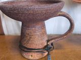 un vase marron posé sur une table sur laquelle se trouve une lampe