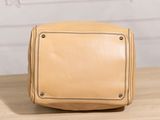 a tan leather bag sitting on top of a wooden table