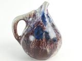 a brown and blue vase with a handle on a white surface