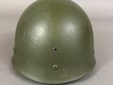 an army green helmet sitting on top of a white surface