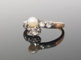 a white pearl and diamond ring on a reflective surface