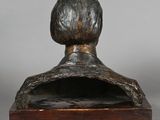 a bronze bust of a woman with a short hair on a wooden base