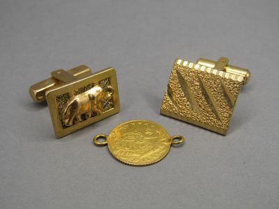 deux boutons de manchette en or et une pièce d'or posés sur une table