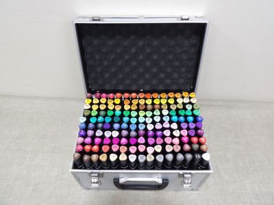 une valise remplie de pots de peinture de différentes couleurs posée par terre