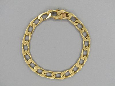 gros plan d'un bracelet en or sur une surface grise