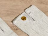 a pair of white gloves with a gold coin on them