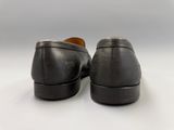 un gros plan sur une paire de chaussures noires posées sur une surface blanche