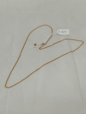 a gold necklace with a tag on it sitting on a white surface