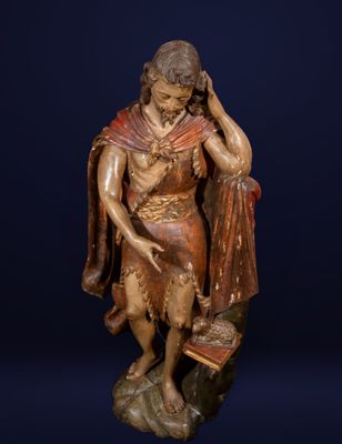an antique wooden statue of a man holding a book on a rock