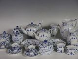 Plusieurs pièces de porcelaine bleue et blanche sont disposées sur une surface blanche