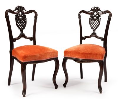 deux chaises avec des coussins rembourrés orange et un dossier sculpté