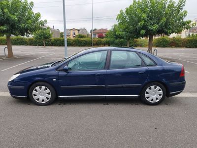 La voiture bleue est garée sur le parking, près des arbres.