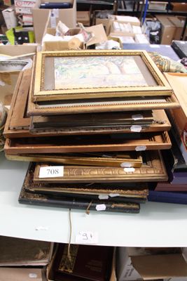 a pile of framed pictures on a table in a room