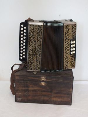 une image représentant un vieil accordéon posé sur une caisse en bois