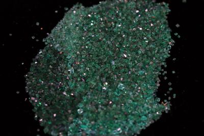 a pile of green crushed glass on a black surface