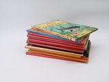 several children ' s books stacked on top of each other on a white surface