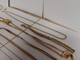 a lot of gold necklaces on a white table