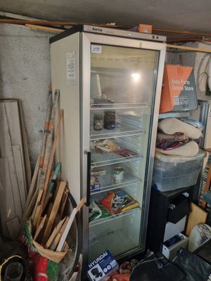 une photo d'un réfrigérateur dans un garage où règne un grand désordre