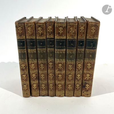 six old books are lined up in a row on a white surface