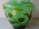 a green vase sitting on a table with a white wall in the background