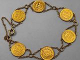 a close up of a gold coin bracelet on a chain