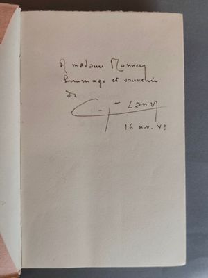 un livre ouvert, sur lequel est posée une note manuscrite, posé sur une table