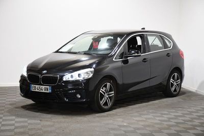 La BMW Tourer noire est garée dans une pièce au sol carrelé.
