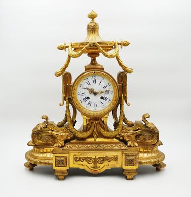 une horloge en or surmontée d'un oiseau