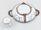 a white and gold plate with a gold handle and a cup