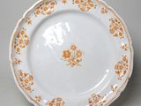 une assiette blanche ornée de fleurs orange, posée sur une table
