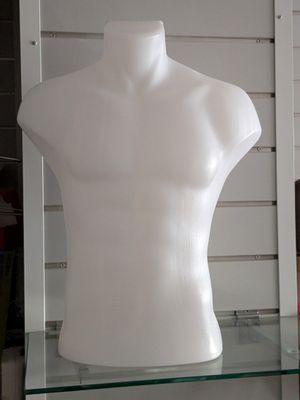 a white mannequin sitting on a glass shelf in a room