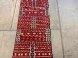 un long tapis rouge posé à même le sol, avec une chaise à l'arrière-plan