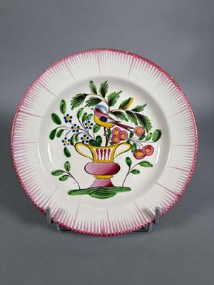 une image représentant une assiette rose et blanche ornée d'un oiseau et de fleurs