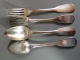 quatre cuillères en argent et une fourchette sont alignées sur une table