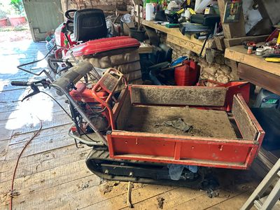 a red cart with dirt in it in a garage