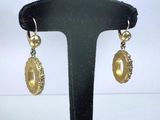 une paire de boucles d'oreilles dorées posées sur un présentoir noir