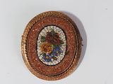 an image of a small gold and enamel broochle on a white surface