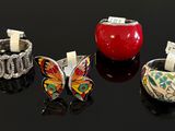 four different colored rings and bracelets on a black surface