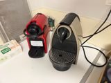 two coffee machines sitting on a counter next to each other