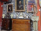 a room with a stone wall, a dresser, a mirror, and a statue