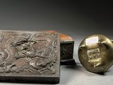 a silver box with a dragon on it next to a golden ball