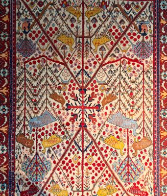 un tapis persan ancien orné d'oiseaux et de fleurs sur fond rouge